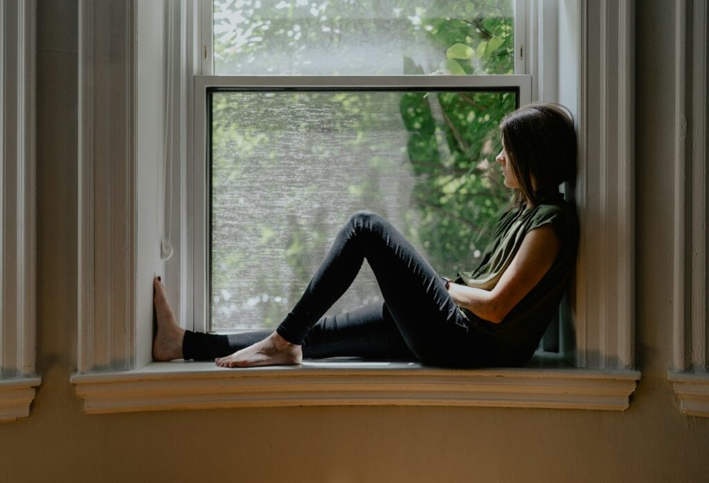 Mujer sentada junto a una ventana con luz natural